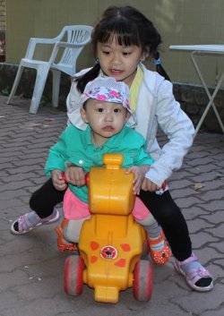 Zwei Kinder sitzen auf einem Spielzeug.